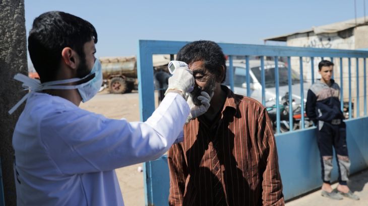 A health worker tests an internally displaced Syrian man as part of security measures to avoid coronavirus, in Azaz