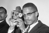 Malcolm X is shown with his 16mm Bell and Howell motion picture camera at JFK International Airport on July 9, 1964, before his departure for Egypt [Matty Zimmerman/AP]