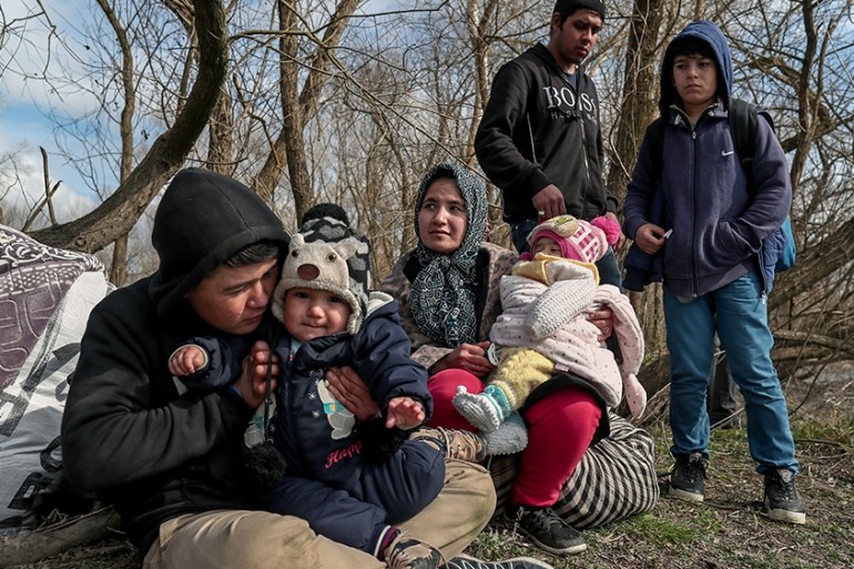 epa08262287 A group of migrants with children rests on the bank of the Meric (Evros) River at the Turkish-Greek border, in Edirne, Turkey, 01 March 2020. Thousands of refugees and migrants are gatheri
