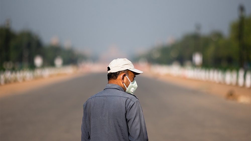 A man wearing a facemask walks along a deserted street during a one-day Janata (civil) curfew imposed as a preventive measure against the COVID-19 coronavirus in New Delhi on March 22, 2020. - Nearly 