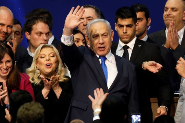 Israeli Prime Minister Benjamin Netanyahu stands next to his wife Sara as he waves to supporters following the announcement of exit polls in Israel''s election at his Likud party headquarters in Tel Av