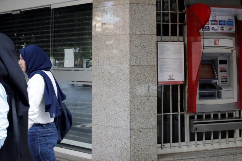 Two women walk past a closed bank office in Beirut, Lebano