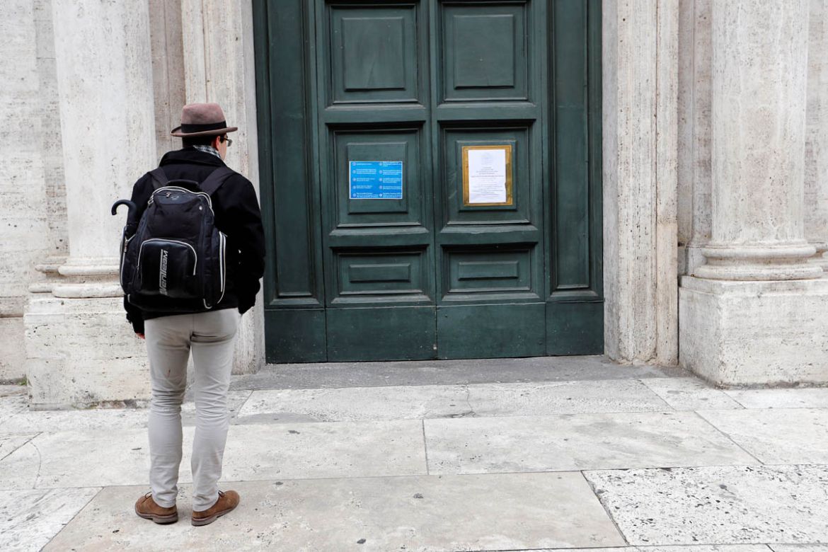 A man looks at the closed entrance of St. Louis of the French, a church in the heart of Rome that has closed as a precautionary measure after a priest who had been working there came down with coronav