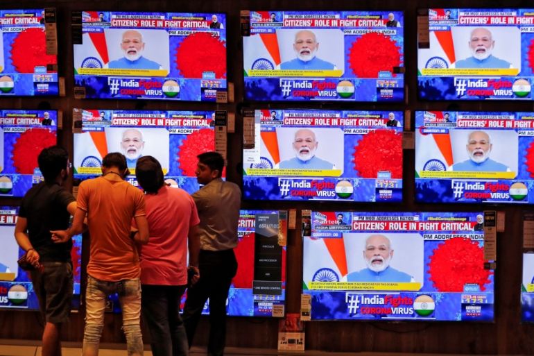 People watch Indian Prime Minister Narendra Modi addressing the nation amid concerns about the spread of coronavirus disease (COVID-19), on TV screens inside a showroom in Ahmedabad