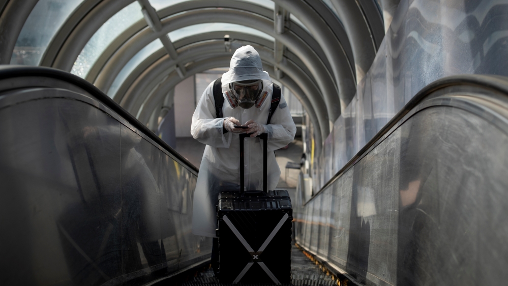 A traveller wearing protective clothing and a full-face mask goes up an escalator after leaving Beijing Railway Station as the country is hit by an outbreak of the novel coronavirus