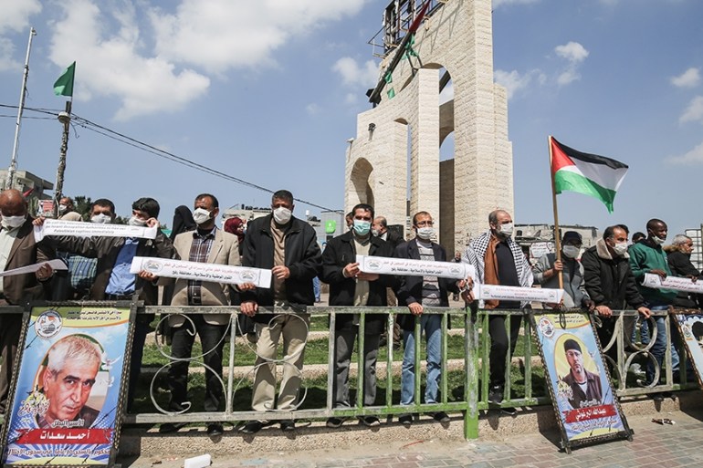 Palestinians, wearing protective masks amid fears of the spread of the novel coronavirus, and waving national flags take part in a protest in solidarity with Palestinian prisoners in Israeli jails out