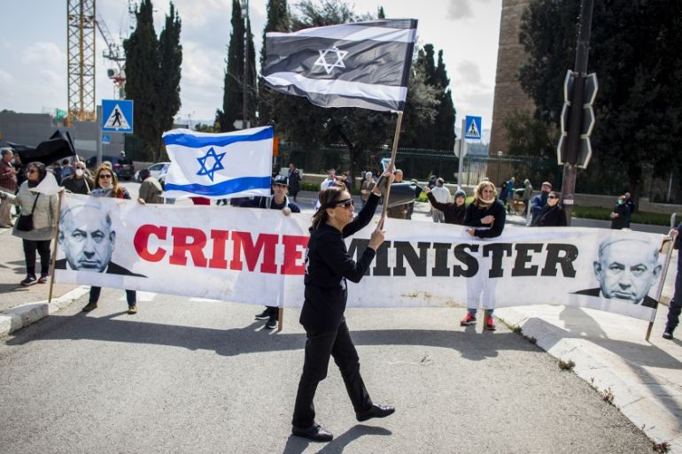 People wave Israeli flags during a protest outside the Israeli parliament in Jerusalem, Thursday, March 19, 2020. Hundreds of people defied restrictions on large gatherings to protest outside parliame