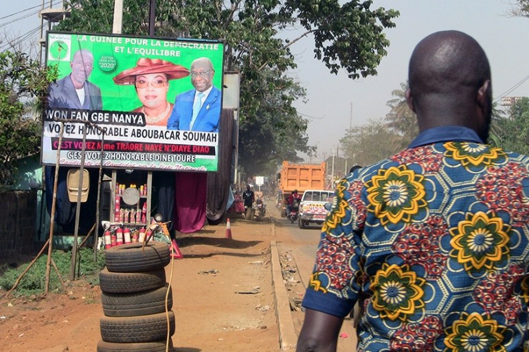 A man walks Legislative''s election campaign poster of Guinea for democracy and harmony party (GDE) in Conakry, Guinea, February 26, 2020.Picture taken February 26, 2020. REUTERS/Stringer