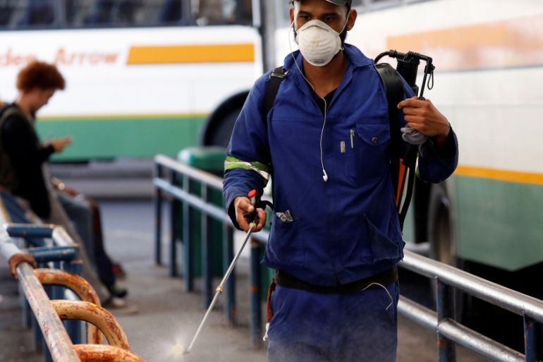 A health worker sprays disinfectant on railings to combat the spread of coronavirus disease (COVID-19) at a bus depot in Cape Town