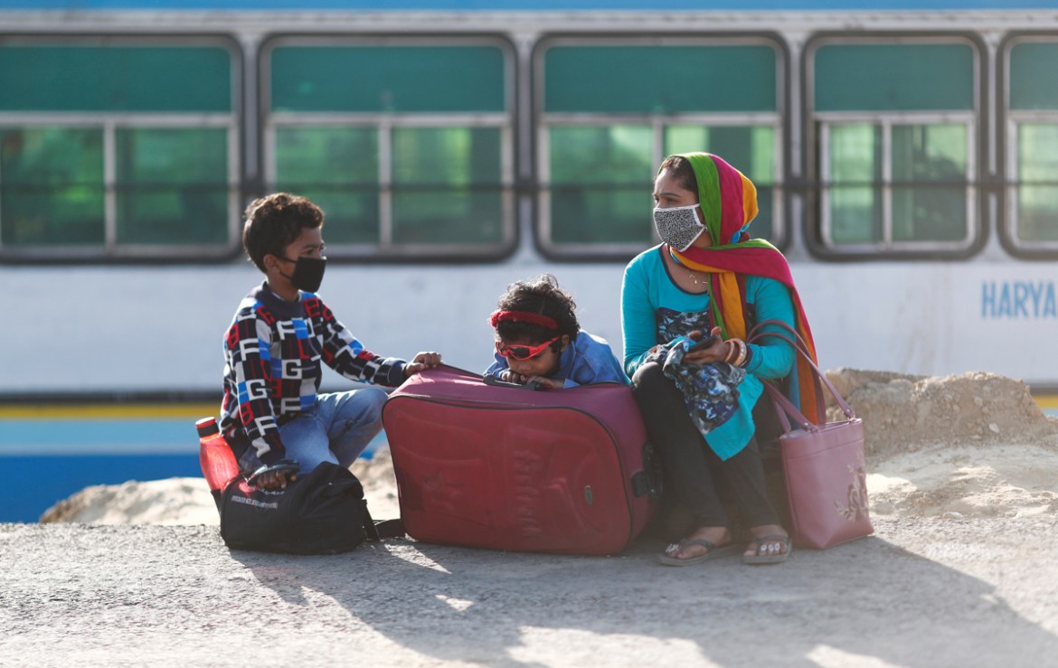 A family of a migrant worker sits along a highway as they wait for a bus to return to their village, during a 21-day nationwide lockdown to limit the spreading of coronavirus disease (COVID-19), in Gh