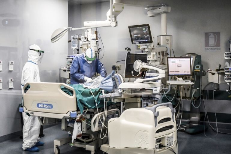 In this photograph taken from behind a window, doctors work on a Covid-19 patient in the intensive care unit of San Matteo Hospital, in Pavia, northern Italy, Thursday, March 26, 2020. The San Matteo