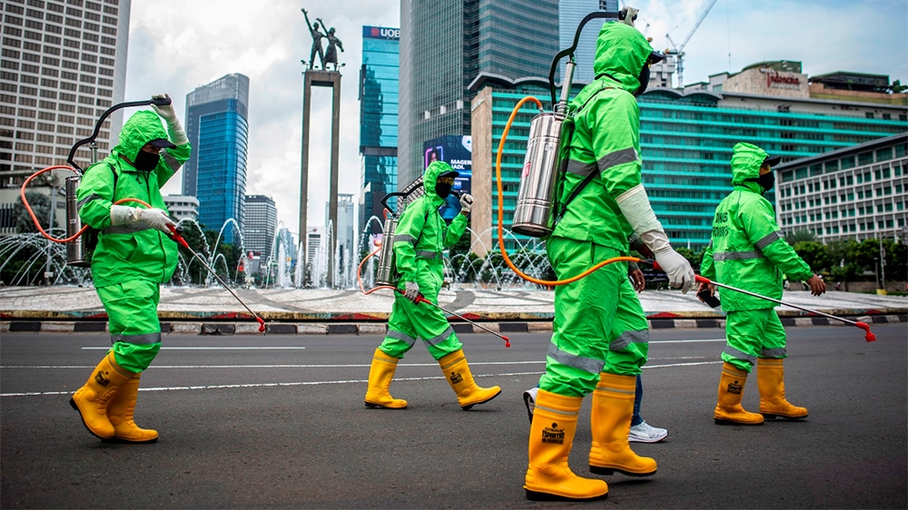 Workers walk in protective suits during an operation of spraying disinfectant to prevent the spread of coronavirus disease (COVID-19) in Jakarta, Indonesia March 22, 2020 in this photo taken by Antara
