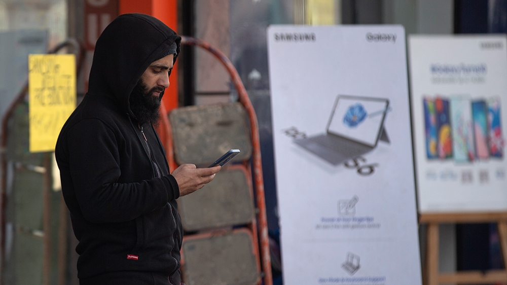 In this Jan. 30, 2020, photo, a Kashmiri man browses the internet on his mobile phone outside a shop in Srinagar, Indian controlled Kashmir. Six months after India stripped restive Kashmir of its semi