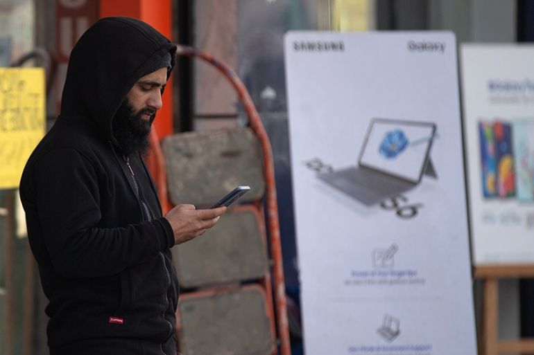 In this Jan. 30, 2020, photo, a Kashmiri man browses the internet on his mobile phone outside a shop in Srinagar, Indian controlled Kashmir. Six months after India stripped restive Kashmir of its semi