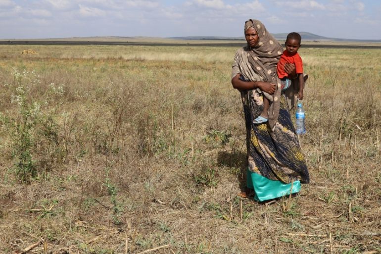 An internally displaced Ethiopian carries her youngest son in her wheat field that was damaged by heavy rains and desert locusts in the outskirts of Tuli Guled