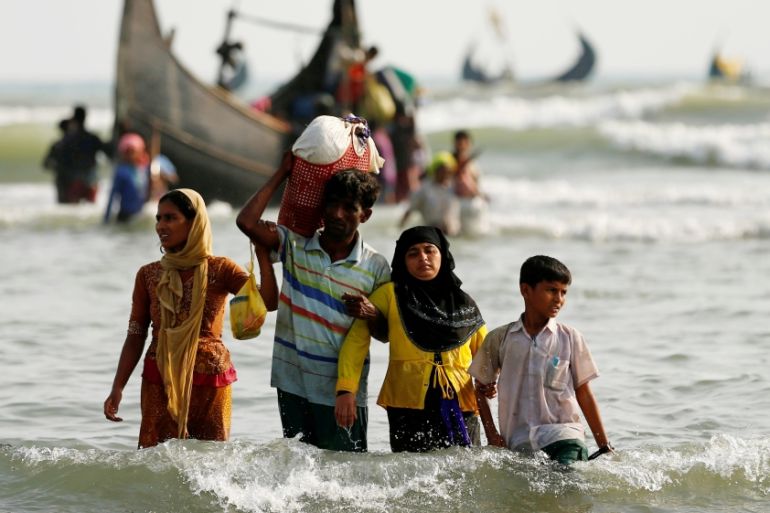 Rohingya refugees walk to the shore with his belongings after crossing the Bangladesh-Myanmar border by boat through the Bay of Bengal in Teknaf