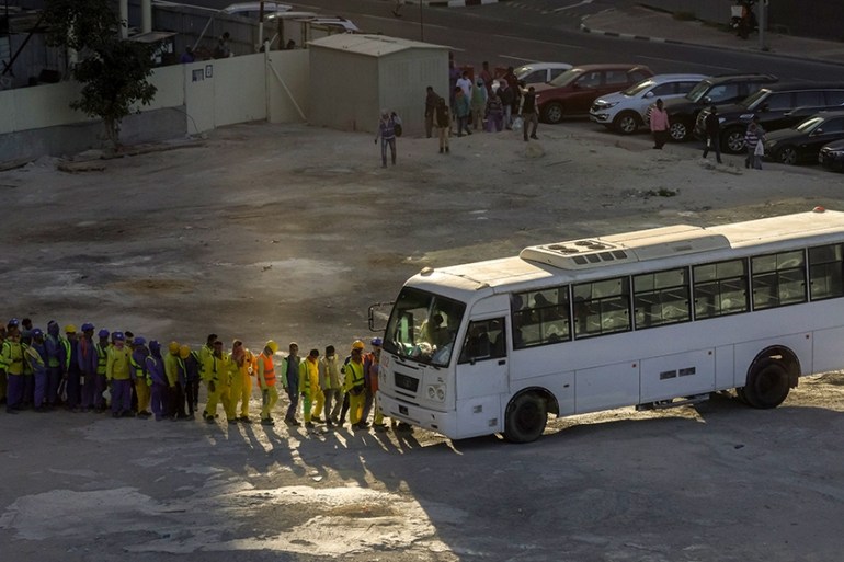 Construction workers queuing to board a bus as their finished their shift on a construction site in Doha, Qatar, March 29, 2020 [Sorin Furcoi/Al Jazeera]
