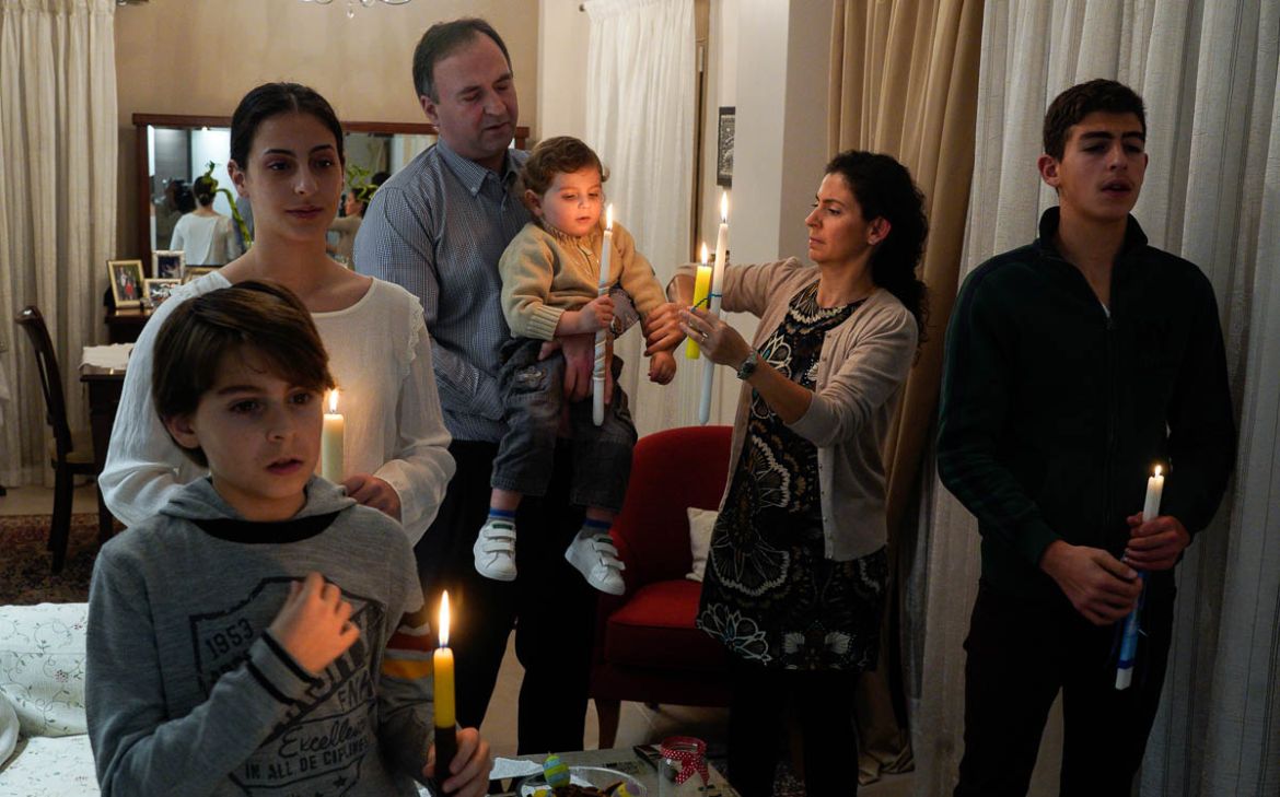 Christos Efstathiou, his wife Evangelia and their four children watch the Greek Orthodox Easter procession on TV in their house, during a lockdown to prevent the spread of the coronavirus disease (COV