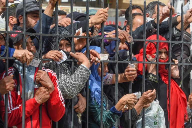 Impoverished Tunisian citizens gather with their identification cards in front of the headquarters of Mnihla delegation in Ariana Governorate outside Tunis on March 30, 2020,
