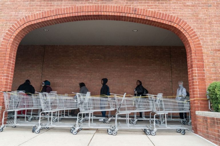 Shoppers line up to enter a supermarket as they practice social distancing in St Louis