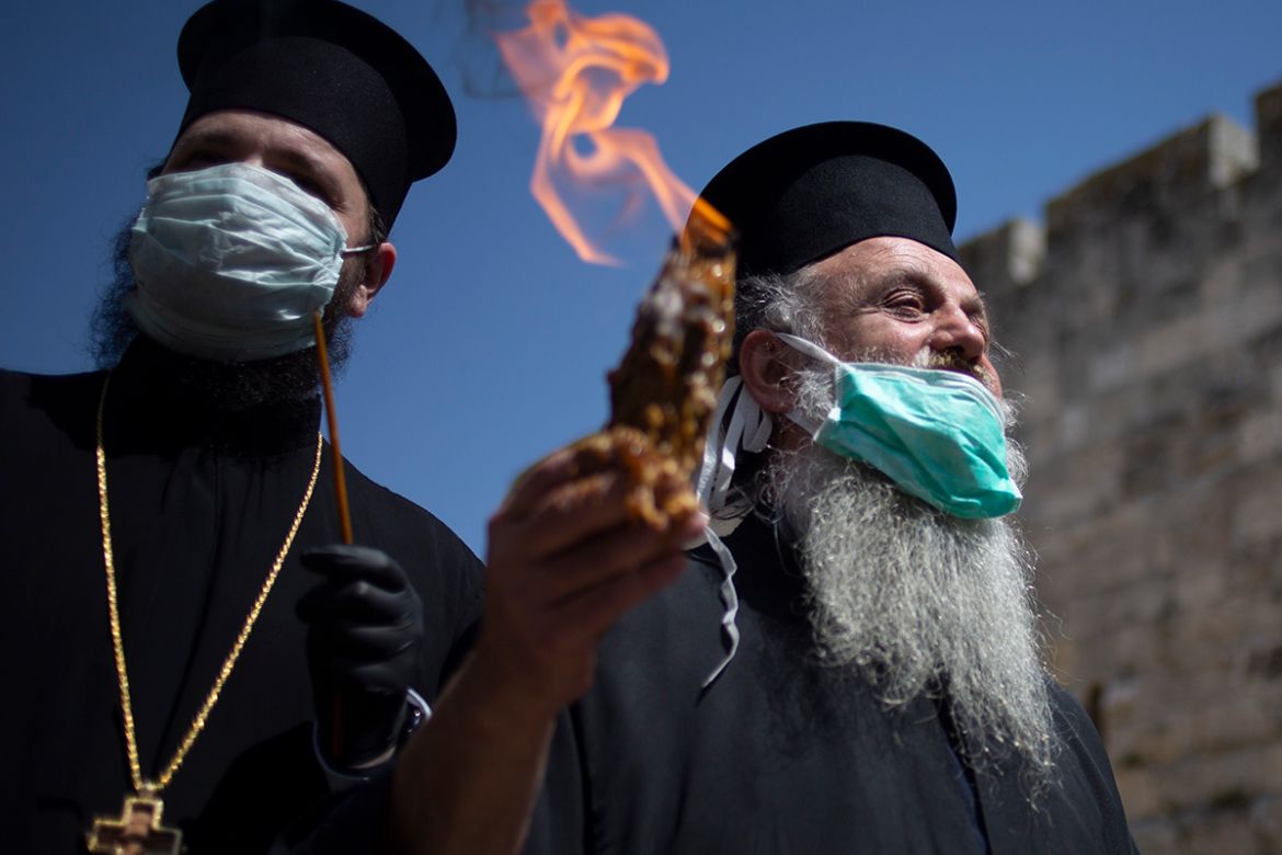 Orthodox clergyman holds holy fire to transfer to predominantly Orthodox countries from the Church of the Holy Sepulchre, traditionally believed by many Christians to be the site of the crucifixion an
