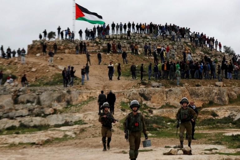 Israeli forces stand guard as Palestinian demonstrators gather during a protest against Israeli settlements in Beita town near Nablus in the Israeli-occupied West Bank