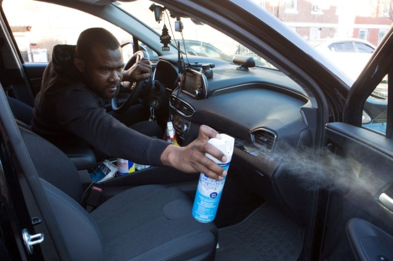 Uber and Lyft driver Adama Fofana sprays disinfectant in his car in New York City