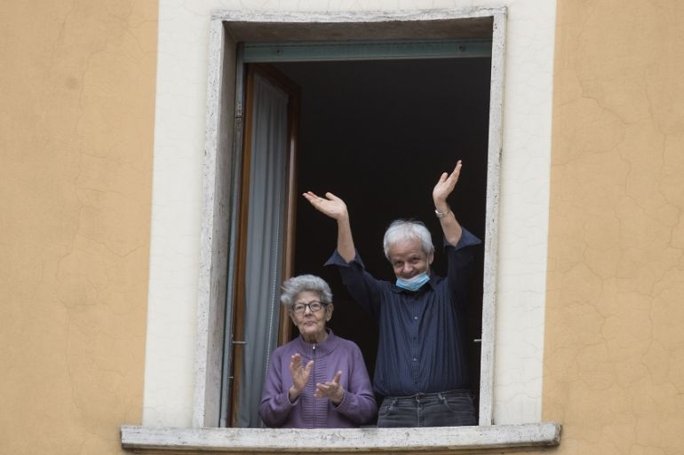 People clap their hands and wave, in Rome, Saturday, March 14, 2020. At noon in Italy, people came out on their balconies, terraces, gardens or simply leaned out from open windows to clap for several