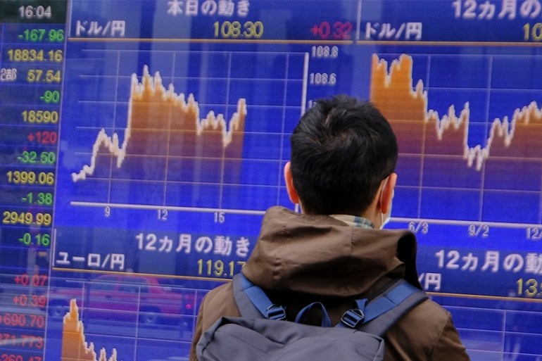 A man looks at movements of the foreign exchange rate against the US dollar (upper) in Tokyo on March 31, 2020. - Tokyo shares closed lower on March 31 in volatile trade, as investors remained nervous