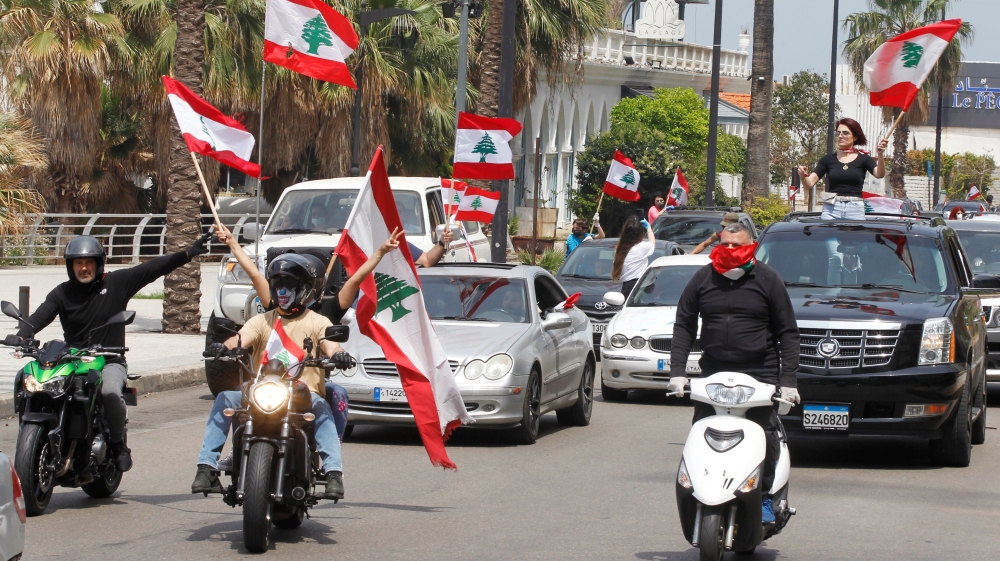 Anti-government demonstrators wave Lebanese flags as they protest in their cars, amid a countrywide lockdown to combat the spread of the coronavirus disease (COVID-19), in Beirut