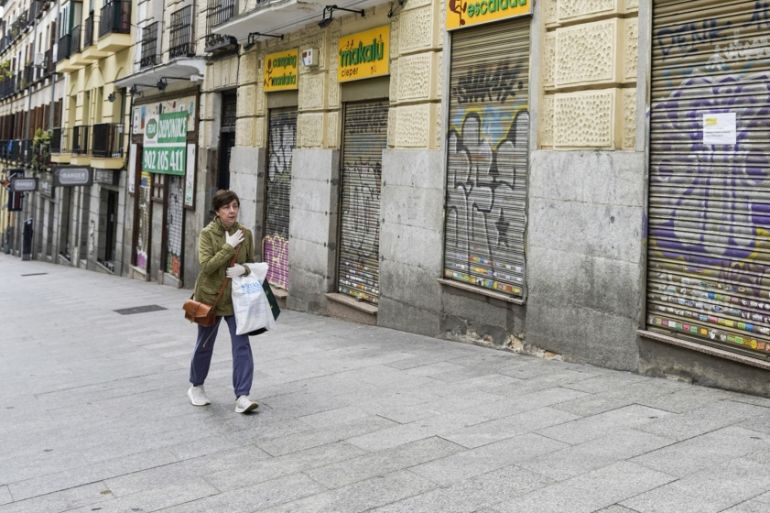 A pedestrian wearing a protective face mask walks by a shuttered outdoor equipment retailer in Madrid, Spain, on Monday, April 13, 2020. Italy, Spain and France reported a slowdown in new coronavirus