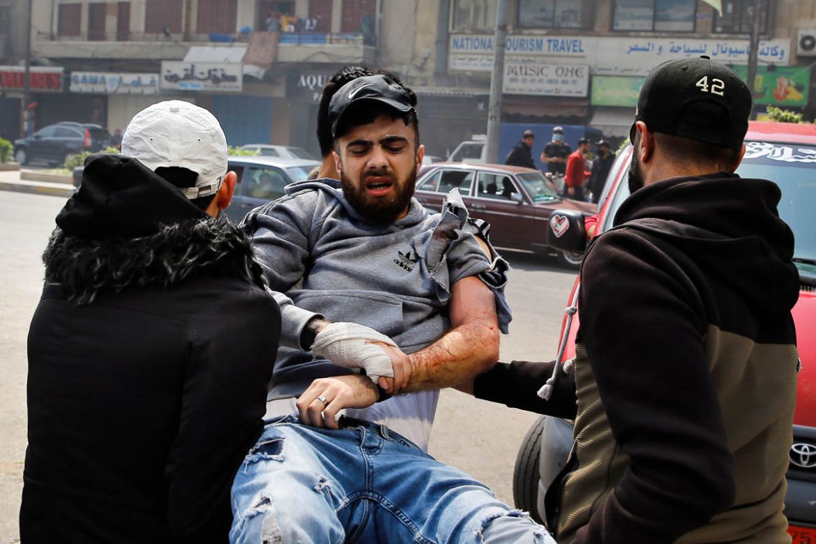 Anti-government protesters carry their friend who was wounded by a rubber bullet during clashes with Lebanese army soldiers, in the northern city of Tripoli, Lebanon, Tuesday, April 28, 2020. Hundreds