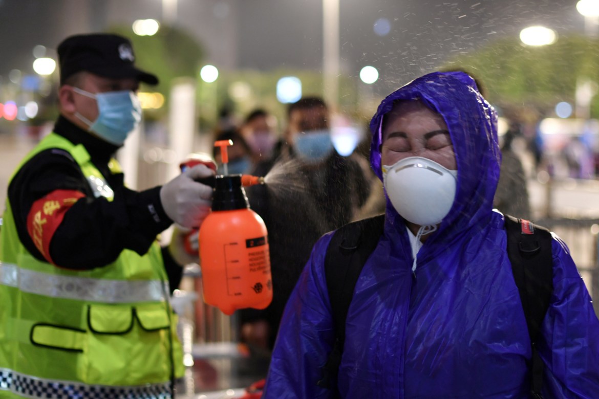 A police officer sprays disinfectant on a traveller outside Hankou Railway Station after travel restrictions to leave Wuhan, the capital of Hubei province and China''s epicentre of the novel coronaviru