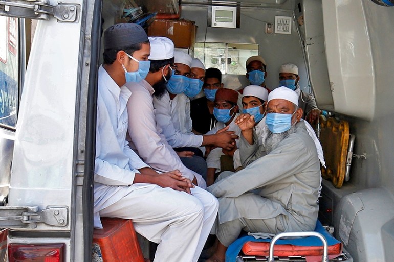 Men, who according to health and police officials had visited three Muslim missionary gatherings including in Nizamuddin area of New Delhi, wearing protective masks sit in an ambulance that will take