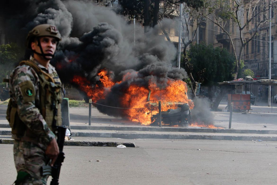 A Lebanese army soldier stands next to a burning car during clashes with protesters in the northern port city of Tripoli on April 28, 2020, as anger over a spiralling economic crisis re-energised a mo