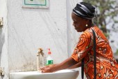 A woman washes her hands, amid the coronavirus disease (COVID-19) outbreak, by the gate of Maitama General Hospital in Abuja, Nigeria on March 19, 2020 [Afolabi Sotunde/Reuters]