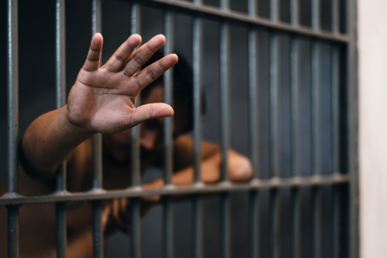 Prisoner Showing Hand While Standing In Prison - stock photo
