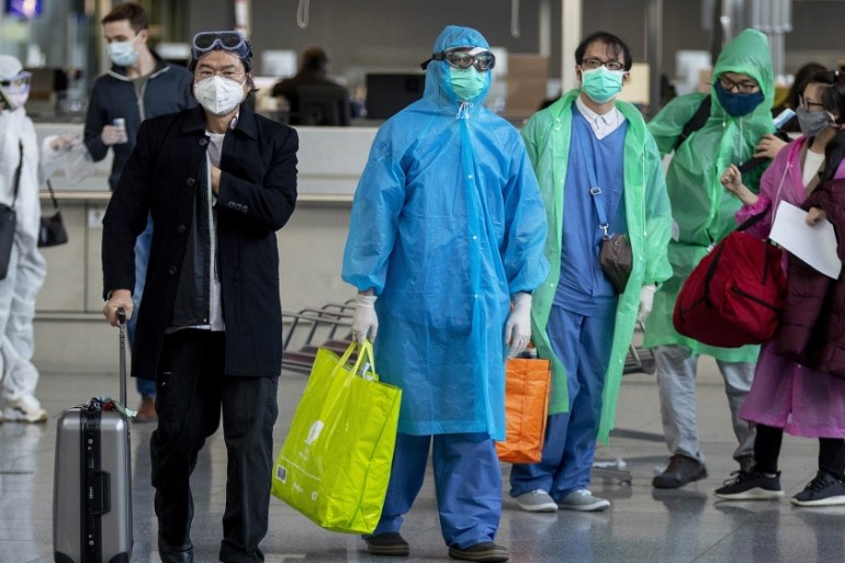Chinese tourists walk to their gate to catch a flight to China at the airport in Frankfurt, Germany, Sunday, March 29, 2020. Due to the coronavirus only a few flights are leaving the airport these day