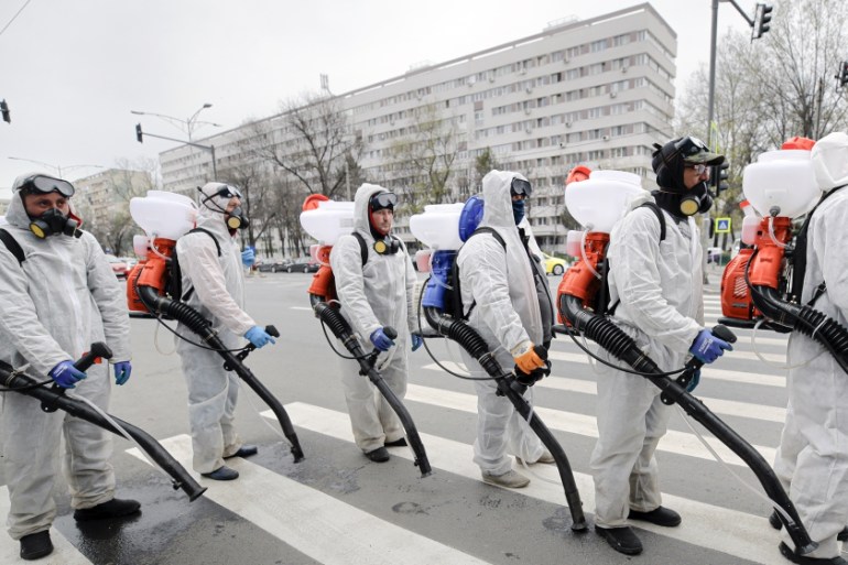Municipal workers wearing protective outfits wait to reload the tanks with chemicals while disinfecting an area of the Romanian capital Bucharest, Romania, Tuesday, March 31, 2020 as authorities attem