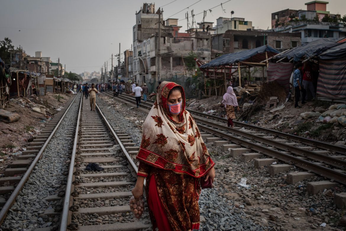 A woman wearing a face mask to protect herself from air pollution walks along railway tracks in Dhaka, Bangladesh, April 29, 2019. The city has one of the worst quality of air on earth where dust, fum