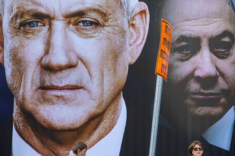 People walk by an election campaign billboard for the Blue and White party, the opposition party led by Benny Gantz, left, in Ramat Gan, Israel, Thursday, Feb. 20, 2020. Prime Minister Benjamin Netany