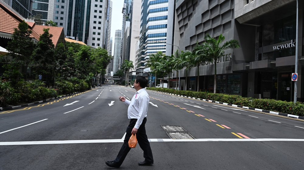 A man crosses an empty street in the central business district of Singapore on April 7, 2020, as the country ordered the closure of all businesses deemed non-essential as well as schools to combat the
