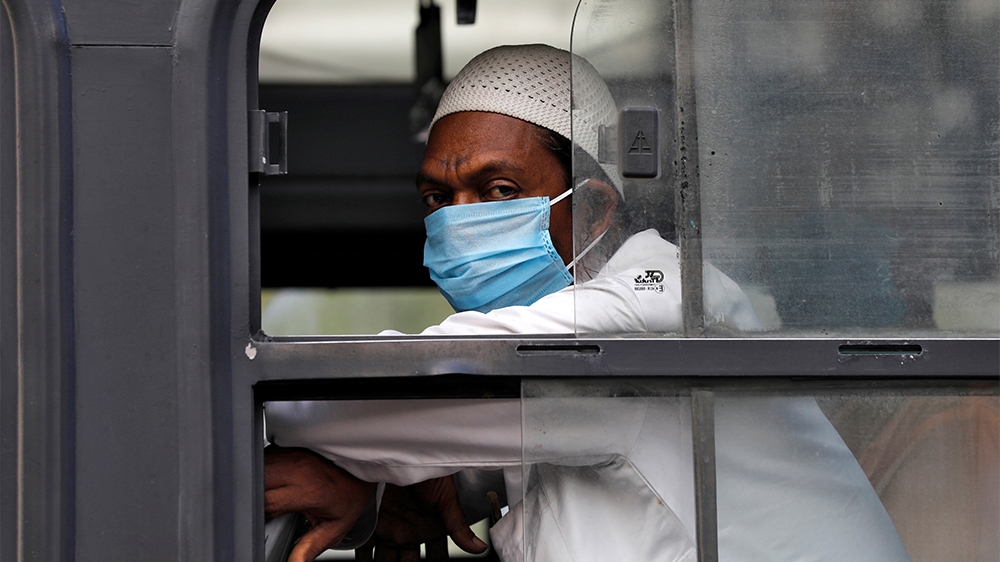 A man wearing a protective mask sits inside a bus that will take him to a quarantine facility, amid concerns about the spread of coronavirus disease (COVID-19), in Nizamuddin area of New Delhi, India,