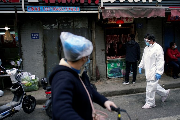 People wearing protective suits is seen at a street market in Wuhan