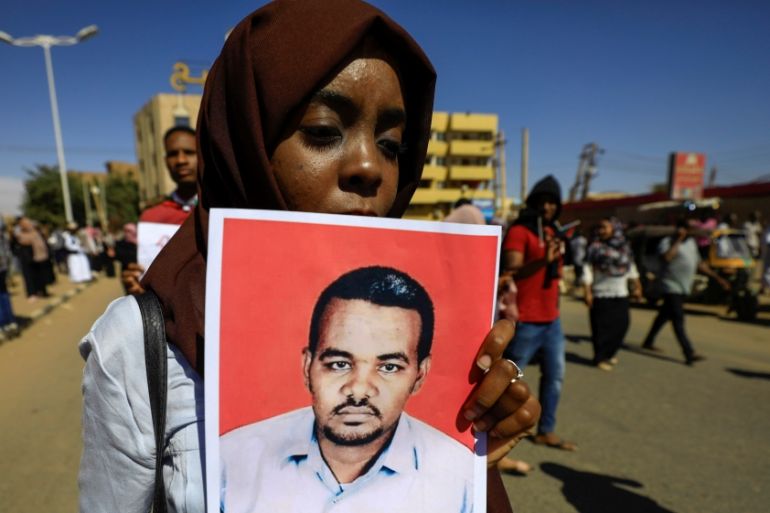 A Sudanese woman carries a portrait of the teacher Ahmed al-Khair as she celebrates outside the court in Omdurman