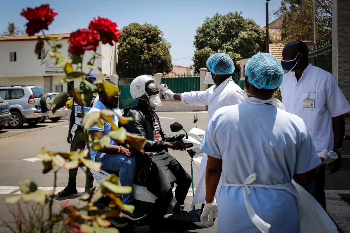 Medical staff and police officers conduct temperature checks at the entrance of the Hôpital Principal of Dakar before allowing patients, visitors and staff to enter. The hospital started receiving Co