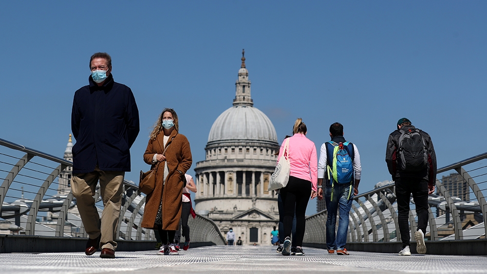 People wearing face masks cross Millennium Bridge, as the spread of the coronavirus disease (COVID-19) continues, in London, Britain, April 25, 2020. REUTERS/Simon Dawson