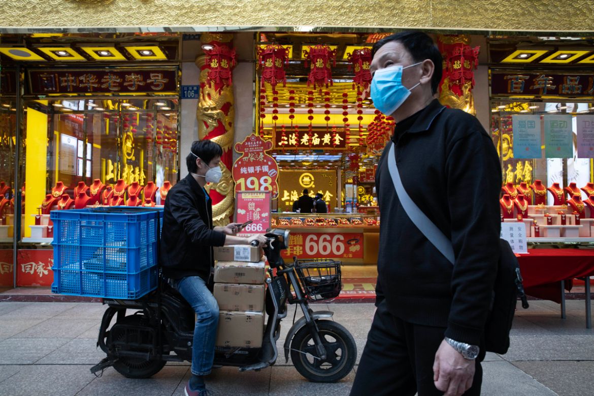 A walks past a delivery man outside a gold jewelry shop on the streets of Wuhan in central China''s Hubei province on Wednesday, April 8, 2020. Streets in the city of 11 million people were clogged wit