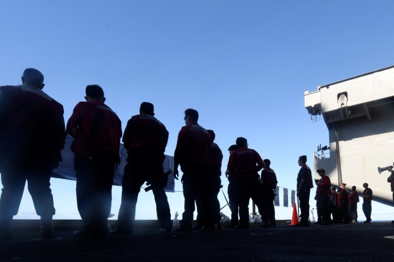 U.S. Navy sailors participate in a small arms qualification aboard the aircraft carrier USS Theodore Roosevelt