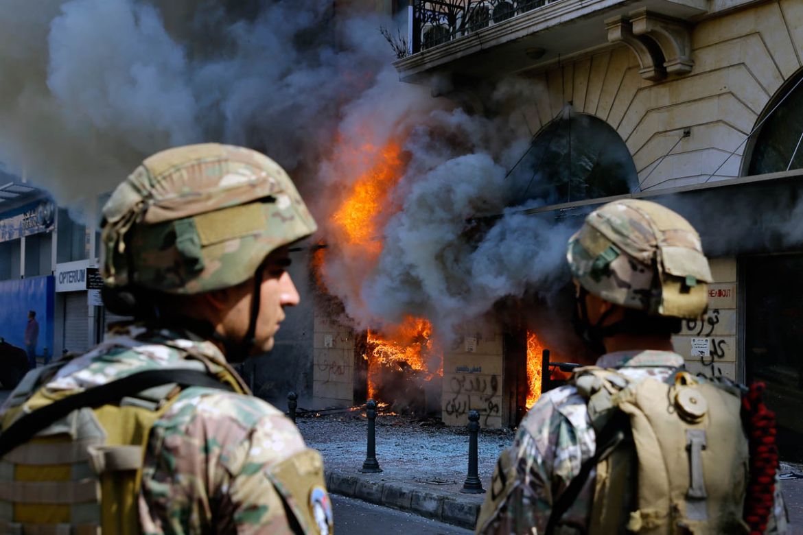 Lebanese army soldiers stand guard in front of a Credit Libanais Bank that was set on fire by anti-government protesters, in the northern city of Tripoli, Lebanon, Tuesday, April 28, 2020. Hundreds of